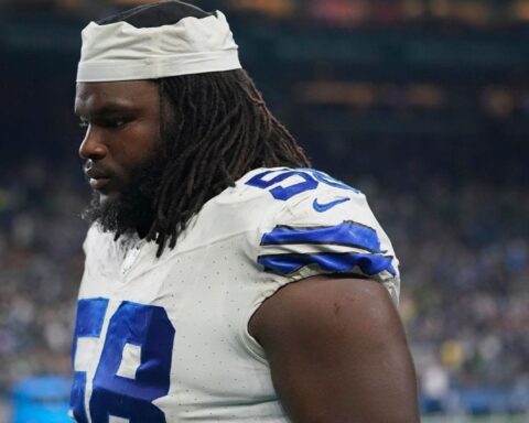 A football player in a white and blue uniform, numbered 68, standing on the field with a focused expression.