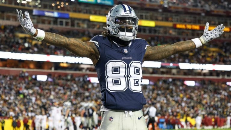 Football player wearing a Dallas Cowboys uniform with arms outstretched on the field during a game.