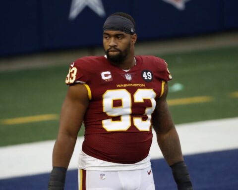 Football player in a red jersey with number 93 stands on the field with a serious expression.