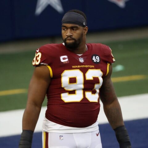 Football player in a red jersey with number 93 stands on the field with a serious expression.