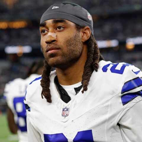 A football player in a white uniform with the number 21 stands on the field, looking ahead.