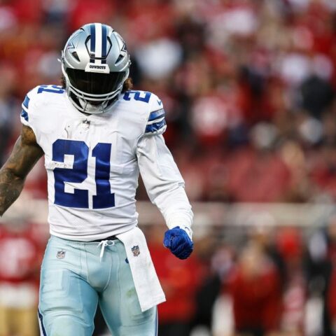 Football player in a blue and white uniform, wearing number 21, walking on a field with a crowd in the background.