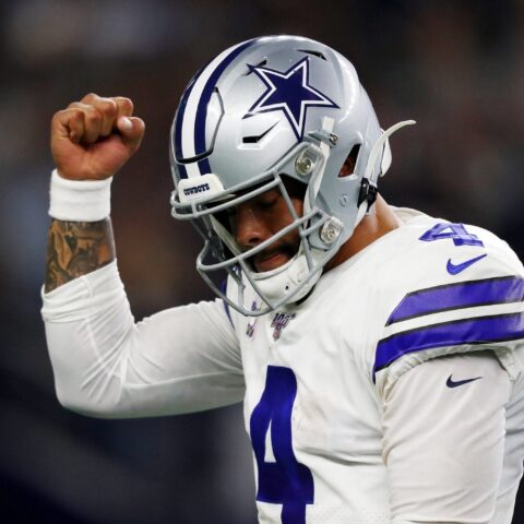 Football player in a Dallas Cowboys uniform raises his fist in a celebratory gesture during a game.