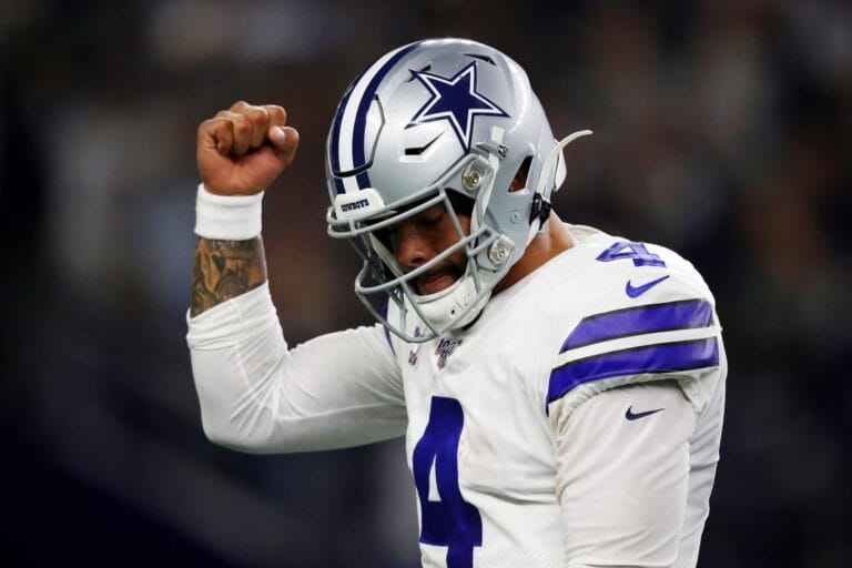 Football player in a Dallas Cowboys uniform raises his fist in a celebratory gesture during a game.