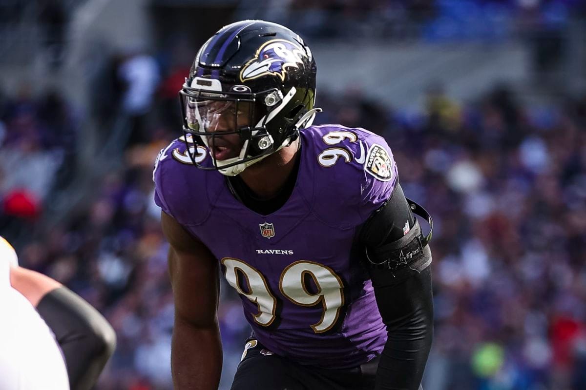 A football player wearing a purple jersey with the number 99 and a Ravens helmet on the field during a game.