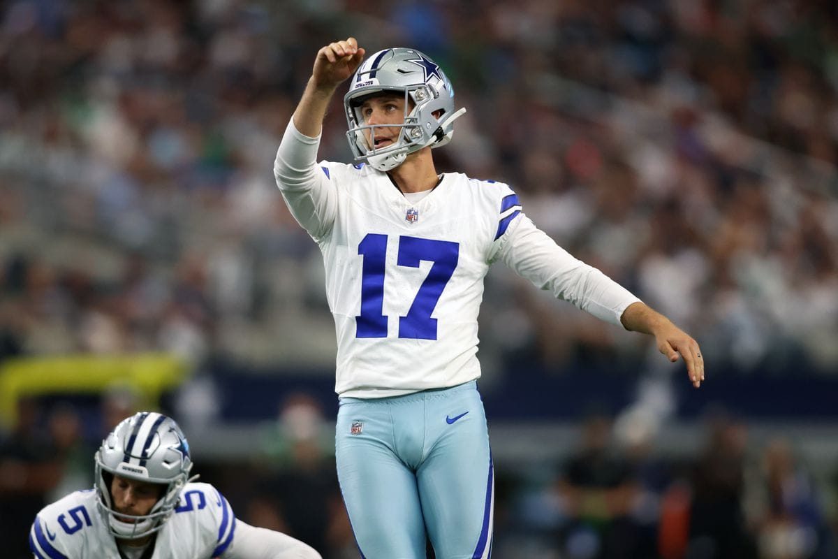 Football player in a Dallas Cowboys uniform prepares to kick the ball during a game.