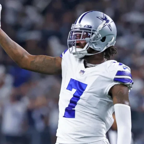 Football player wearing a white and blue Dallas Cowboys uniform with the number 7 raises his left arm during a game.