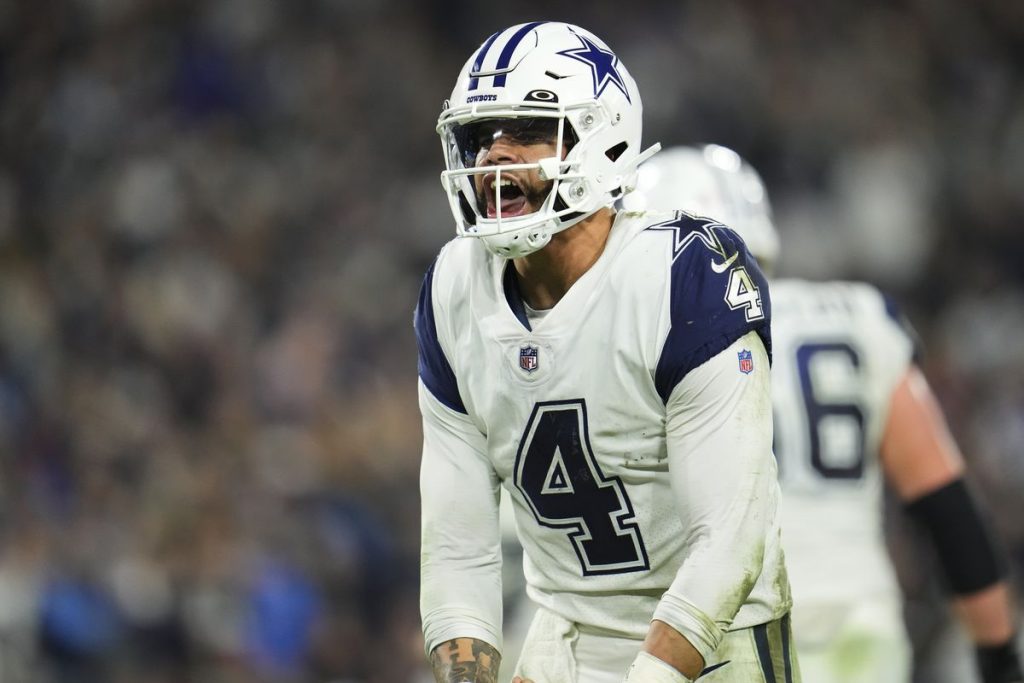 A football player wearing a Dallas Cowboys uniform and helmet appears to be shouting during a game.