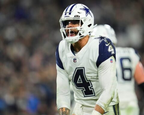 A football player wearing a Dallas Cowboys uniform and helmet appears to be shouting during a game.