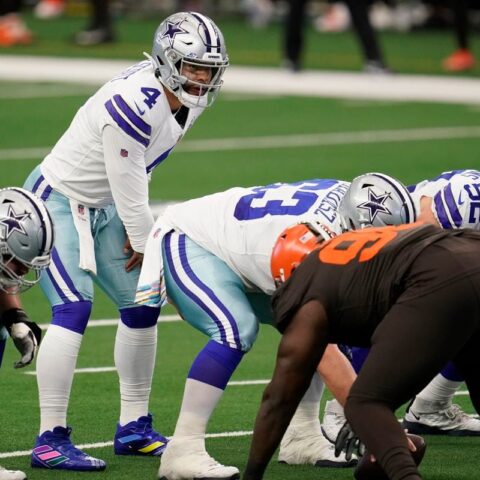 Football players from the Cowboys and Browns teams are lined up at the line of scrimmage during a game.