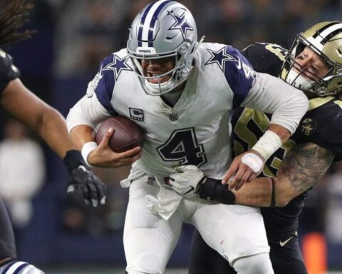 Football player in a white jersey is being tackled by a player in a black jersey during a game.