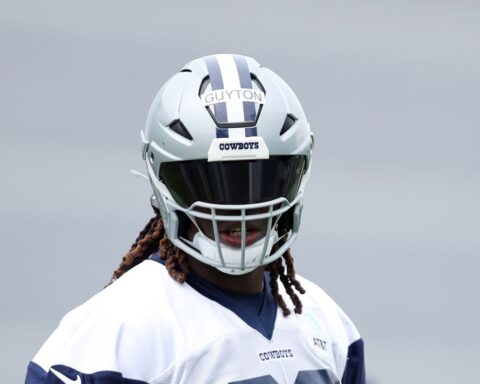 A football player in a Cowboys helmet with a tinted visor and a jersey labeled "GUYTON.