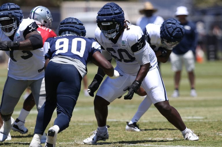 Football players, including Tyler Guyton, in padded gear are practicing diligently on the field.