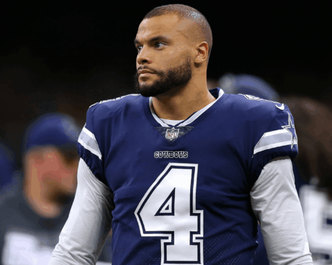 A football player in a blue Cowboys jersey with number 4 stands on the field.