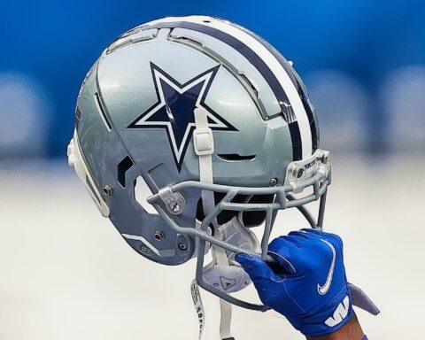 A football helmet with a star logo, iconic to the Cowboys, is triumphantly held aloft by a gloved hand.