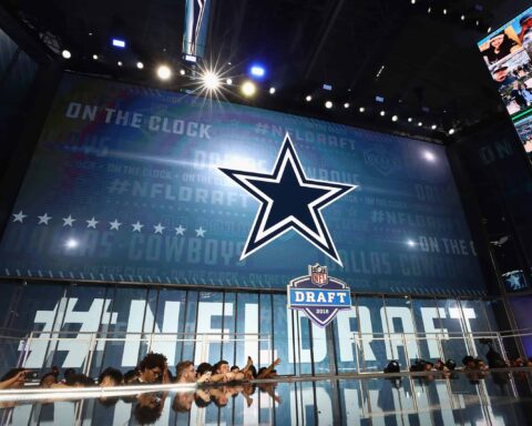 At the NFL Draft stage, the Dallas Cowboys logo stands prominently, as fans eagerly anticipate which future prospect will be selected in this pivotal round.