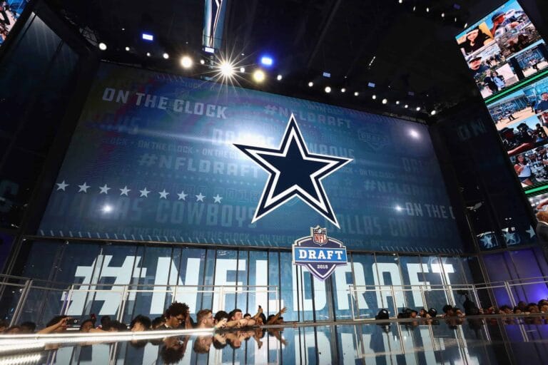 A stage with the Dallas Cowboys logo and "NFL Draft" sign, with people in the foreground.