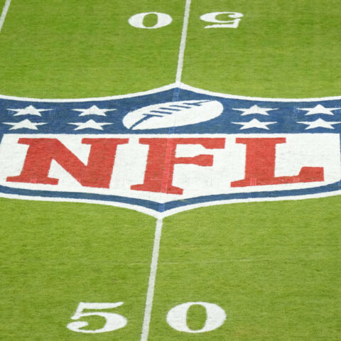 The NFL logo proudly adorns the 50-yard line, flanked by yard markers on lush green turf, as if waiting for a flawless play from the Dallas Cowboys.