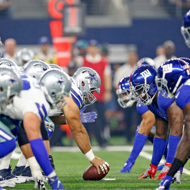 Football players in blue and white uniforms face off at the line of scrimmage during a Dallas Cowboys game.