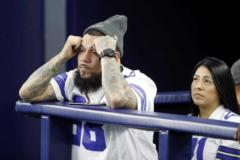 A man and woman in sports jerseys intently watch the DAL vs SF game, their faces tense and focused.