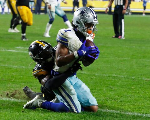 In Week 8, a Cowboys football player in white and blue uniform clutches the ball tightly while being tackled by a player in black and yellow uniform.