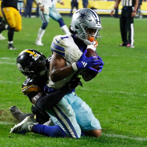 In Week 8, a Cowboys football player in white and blue uniform clutches the ball tightly while being tackled by a player in black and yellow uniform.