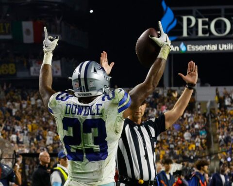 Football player celebrating a touchdown as a referee signals in a crowded stadium.