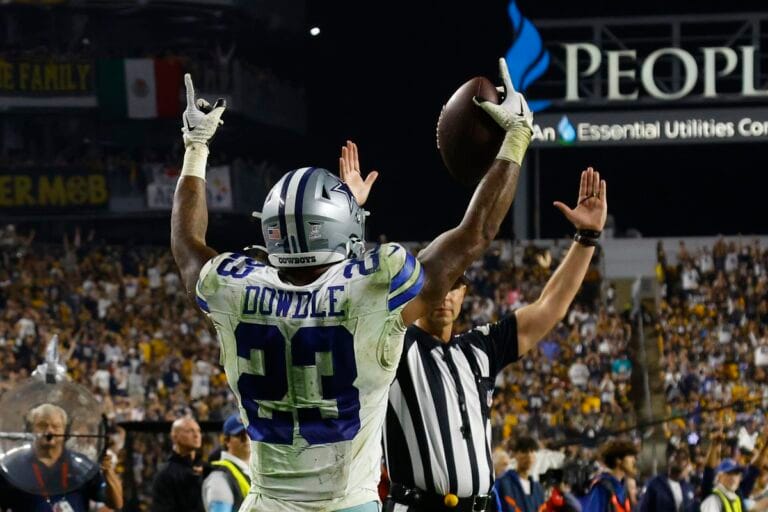 Football player celebrating a touchdown as a referee signals in a crowded stadium.