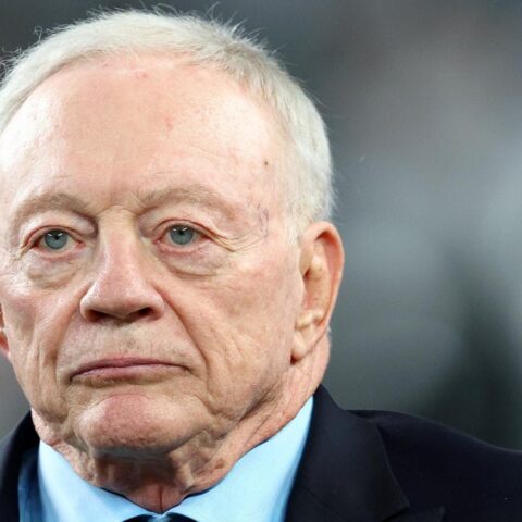 A man in a suit and tie looks ahead with a serious expression.