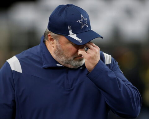 A person in sports attire, perhaps a nod to the Cowboys during their final season, wears a baseball cap and covers their face with one hand.
