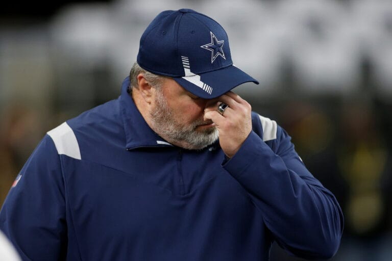 A person in sports attire, perhaps a nod to the Cowboys during their final season, wears a baseball cap and covers their face with one hand.