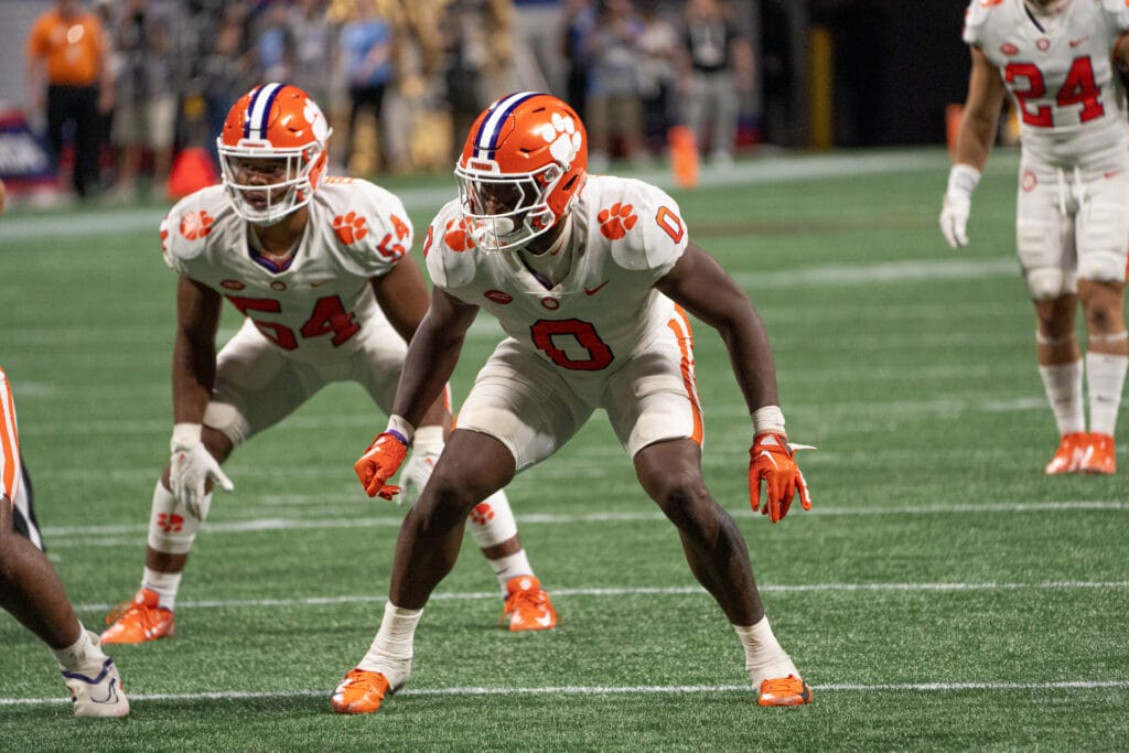 Football players in white uniforms, reminiscent of the Dallas Cowboys, focus intently on the action unfolding on the green field.