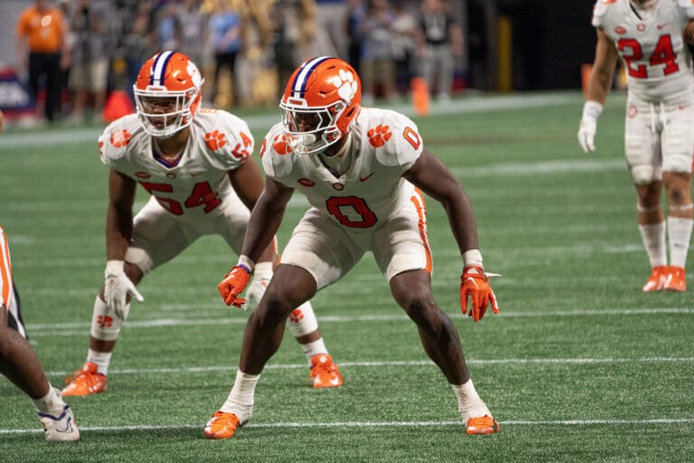 Football players in white uniforms, reminiscent of the Dallas Cowboys, focus intently on the action unfolding on the green field.