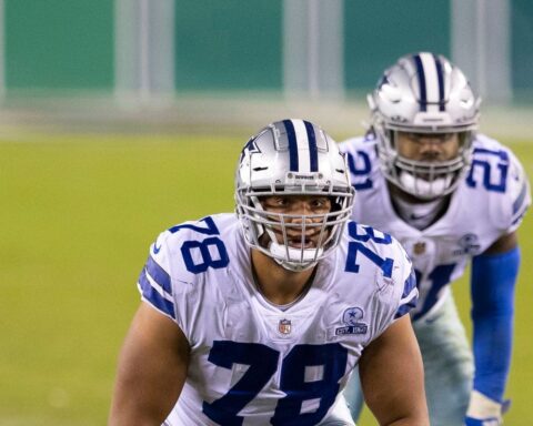 Two veteran football players from the same team stride confidently onto the field, donning their blue and white uniforms and helmets, ready to tackle the challenges of the 2024 season.