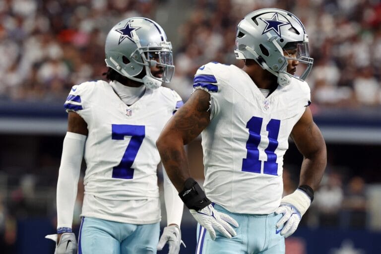 Two American football players in Dallas Cowboys uniforms stand poised on the field during a Week 12 game, showcasing the strength of the Cowboys defense.