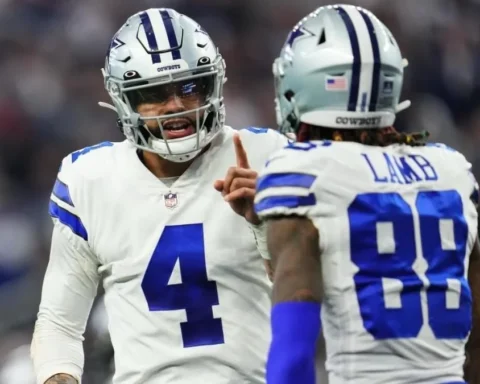 Two football players in Dallas Cowboys uniforms, with Dak Prescott leading the animated conversation, are on the field.