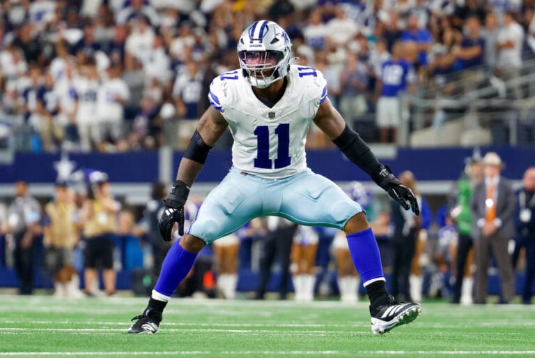 A Dallas Cowboys football player in uniform braces for a play on the field, eyeing the Falcons with determination, as fans glance nervously at the injury report.