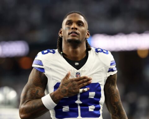 Football player wearing a white jersey with number 88, resembling CeeDee Lamb from the Cowboys, stands with his right hand on his chest as if in a heartfelt moment during Week 11.