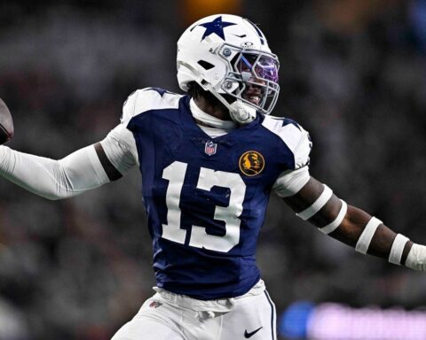 During a game, a football player in a blue and white uniform from the Cowboys draft class throws a precise pass, highlighting the team's 2024 resurgence.