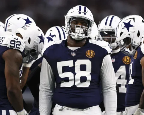Football players in blue and white uniforms, reminiscent of the Cowboys, huddle on the field during a game.