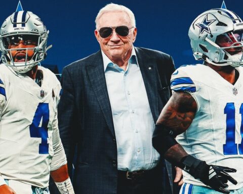 a man standing next to football players
