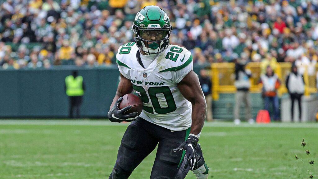 New York Jets player in a white jersey with the number 20 running the football. Breece Hall to the Cowboys: Trade Scenario, Stats, and 2025 Impact