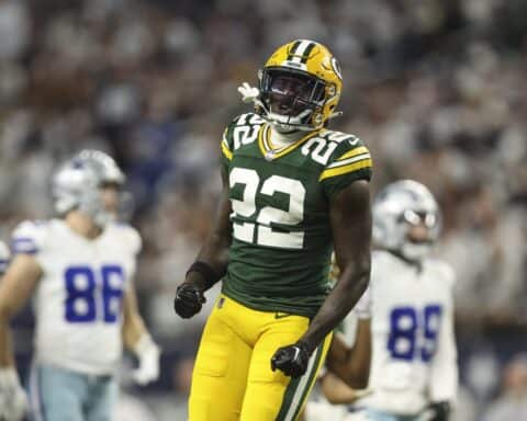 A Packers player wearing a green #22 jersey celebrates a big play with 3 Dallas Cowboys in the background