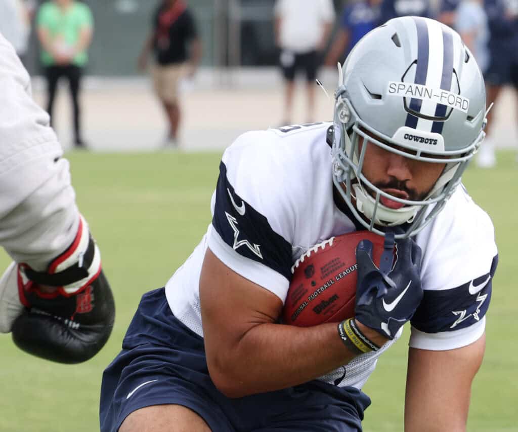 Emerging player Spann-Ford is in the driver's seat for TE2 - Brevyn Spann-Ford, Tight End Dallas Cowboys TE Brevyn Spann-Ford, wearing a white practice jersey, carries the football and braces for impact from a defender