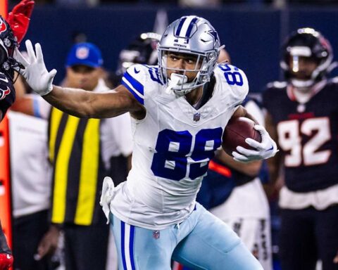 Dallas Cowboys TE Brevyin Spann-Ford, wearing a white #89 jersey carries the football and attempts to stiff arm a defender