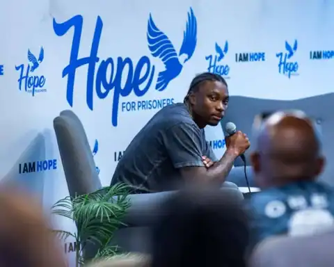 Former NFL WR Henry Ruggs sits holding a microphone during an event