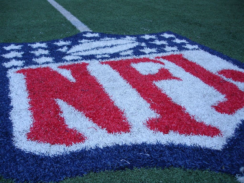 The NFL logo on a football field. Quarterback Mystery: Who's Really the Better Star?