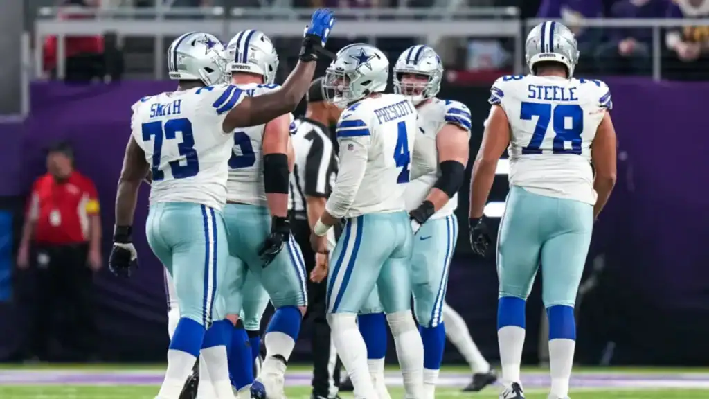 Dallas Cowboys players in white jerseys and silver pants huddling and celebrating The Dak Prescott "No Excuses" Double Standard is Flawed