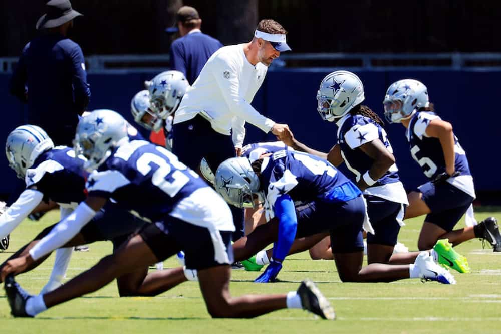 Dallas Cowboys head coach Brian Schottenheimer talking to players as they stretch before practice. Cowboys Fans Shouldn't Panic After 1st Preseason Game