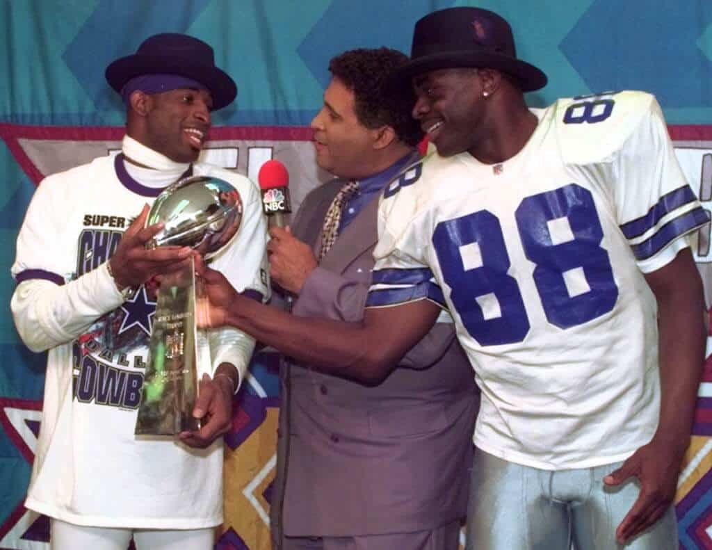 Dallas Cowboys players Michael Irvin and Deion Sanders holding the 1996 Super Bowl Trophy. How No Salary Cap Fueled the Cowboys' 90s Dynasty